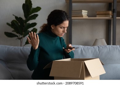 Unhappy young Latino woman unpack box get wrong order shopping online on cellphone. Upset Hispanic female buyer client confused by mistake error buy on internet on smartphone. Bad delivery concept.