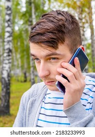 Unhappy Young Man With A Phone In The Autumn Forest