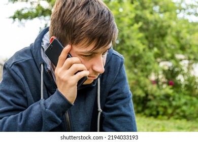 Unhappy Young Man With A Phone In The Summer Park