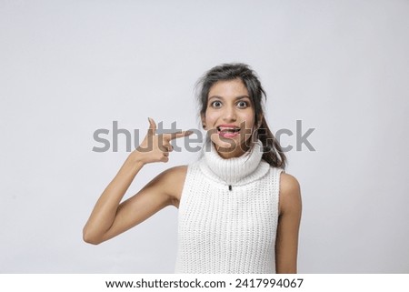 unhappy young Pakistani girl pointing a finger on her tongue