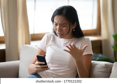 Unhappy Young Vietnamese Woman Feeling Annoyed Looking At Smartphone Screen, Frustrated About Slow Internet Connection Or Getting Spam Scam Message, Bad Phone Work, Broken Gadget, Software Problem.