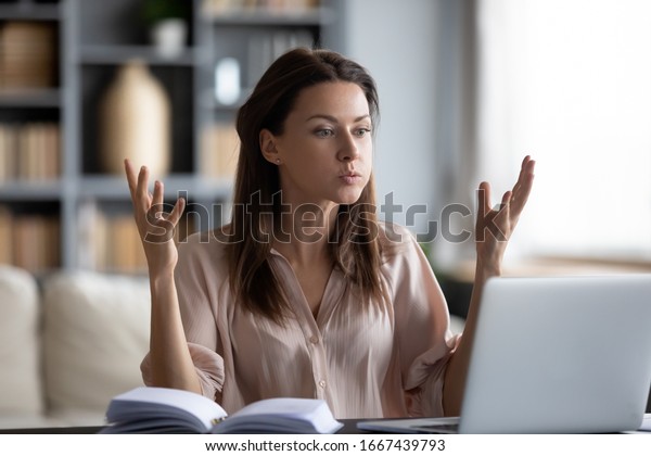 Unhappy young woman looking at laptop screen,\
irritated by bad gadget work, low internet connection, working\
remotely at home. Stressed attractive lady annoyed by hard work\
task or system crash.
