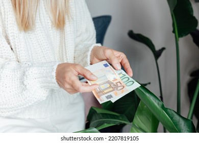 Unhappy Young Woman Wearing Warm Clothing At Home And Counting Cash Money. Energy Crisis In Europe Due To Inflation And War. Increase In The Price Of Natural Gas For Home Heating. 