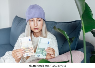 Unhappy Young Woman Wearing Warm Clothing At Home And Counting Cash Money. Energy Crisis In Europe Due To Inflation And War. Increase In The Price Of Natural Gas For Home Heating. 