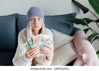 Unhappy Young Woman Wearing Warm Clothing At Home And Counting Cash Money. Energy Crisis In Europe Due To Inflation And War. Increase In The Price Of Natural Gas For Home Heating. 