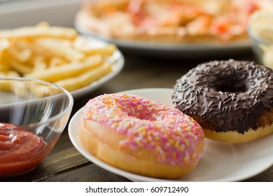 Unhealthy concept. unhealthy food: Burger, sauce, potatoes, donuts, pizza. Close up.