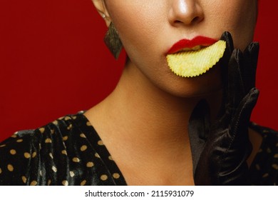 Unhealthy Eating. Junk Food Obsession Concept. Portrait Of Fashionable Luxurious Young Woman Holding, Eating Fried Potato Chips, Posing Over Red Background. Close Up. Studio Shot