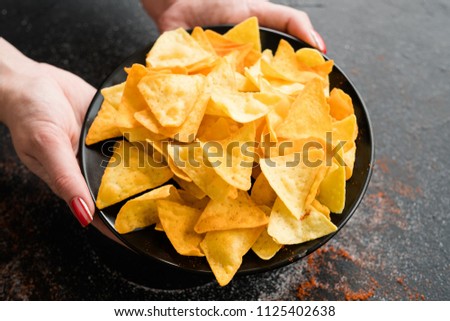 unhealthy fast food snacks. bad eating habits. woman hands holding crispy delicious nacho chips on a plate.