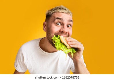 Unhealthy Food Concept. Funny Guy Eating Burger, Eyes Wide Open, Close Up