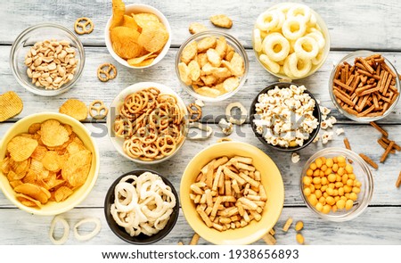 Unhealthy food. pretzels, various chips, croutons, cookies in bowls. unhealthy food for figure, heart, skin, teeth. An assortment of fast carbohydrates. On a wooden background