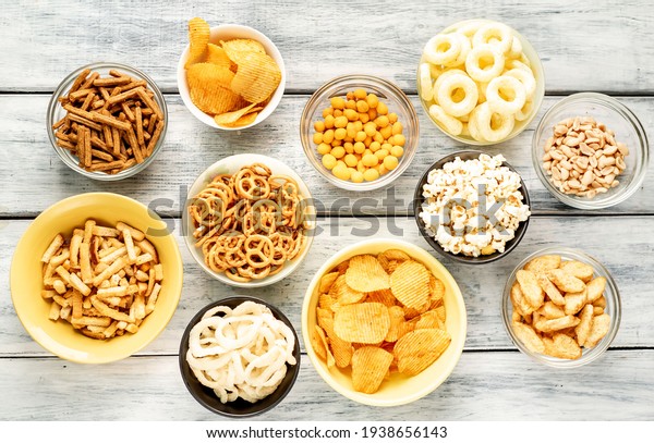Unhealthy\
food. pretzels, various chips, croutons, cookies in bowls.\
unhealthy food for figure, heart, skin, teeth. An assortment of\
fast carbohydrates. On a wooden\
background