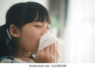 Unhealthy kid blowing nose into tissue, Child suffering from running nose or sneezing, A girl catches a cold when season change, childhood wiping nose with tissue