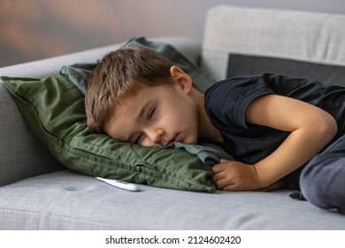 Unhealthy Little Boy Child Measure High Temperature With Thermometer Sleep In Bed Relax At Home In Bedroom. Sick Ill Little Kid Suffer From Flu Fever Asleep In Bed On Lockdown Quarantine.