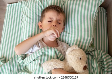 Unhealthy little boy child sleep in bed relax at home in bedroom. Sick ill little kid suffer from flu fever asleep in bed on lockdown quarantine. portrait of a coughing child. - Powered by Shutterstock