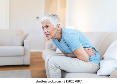 Unhealthy mature woman holding belly, feeling discomfort, health problem concept, unhappy older female sitting on bed, suffering from stomachache, food poisoning, gastritis, abdominal pain, climax - Shutterstock ID 2158239887