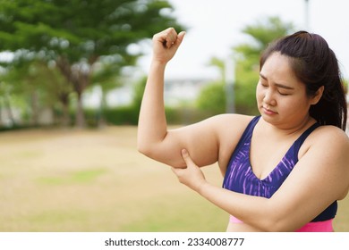 Unhealthy overweight Asian fat woman catching on her big belly and arm close up, woman concerned about her fat and body shape problem.