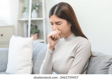 Unhealthy sickness asian young woman, girl unwell with coughing, have cold, sore throat on sofa, couch at home, suffering with symptom cough feeling bad. Health care of Coronavirus, covid-19 concept. - Powered by Shutterstock