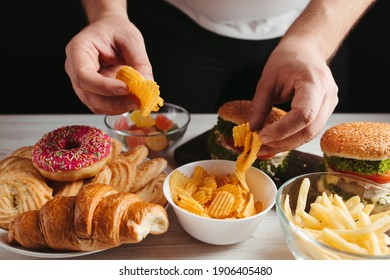 Unhealthy snack, junk food, compulsive overeating. Man overeating unhealthy meals taking hamburger and potato chips from plate
