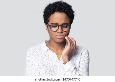 Unhealthy Upset Millennial Ethnic Woman Suffering From Strong Tooth Ache, Feeling Dental Pain Head Shot. Young Sick Unhappy Girl Touching Cheek, Painful Face Expression, Isolated On Grey Background.