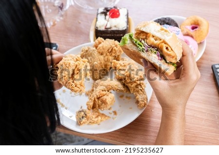 unhealthy woman eating fast food burgers, fried chicken, donuts and desserts, binge eating disorder concept