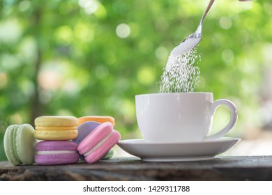 Unhealthy Woman Hand Pouring Sugar In To Coffee Cup With Macarons On Desk ,sugar Addict Concept