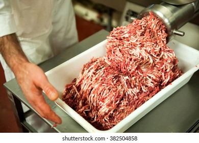 Unidentifiable Butcher Holding Tray Full Of Minced Raw Red Meat Leaving Machine In Food Processing Plant