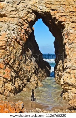 An unidentifiable Caucasian women walking into the sea at "Arch Rock" at Keurboomstrand, near Plettenberg Bay South Africa. 