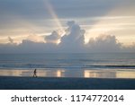 Unidentifiable man walking on the beach. Thinking. Relaxing. Beautiful sunset at jacksonville beach, sun going down at the sea, sun rays through the couds. 