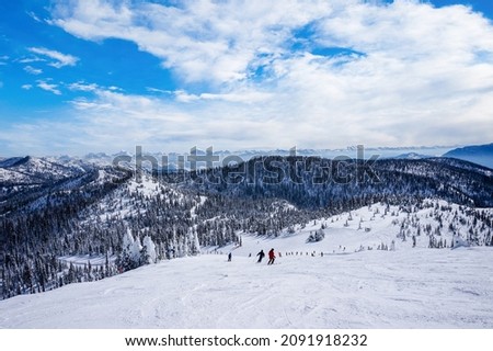 Unidentifiable skiers going down from the summit at Big Mountain in Whitewish, Montana, west of Glacier National Park, USA.