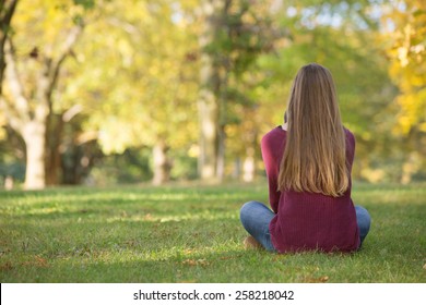 Unidentifiable Woman Sitting Cross Legged On Grass