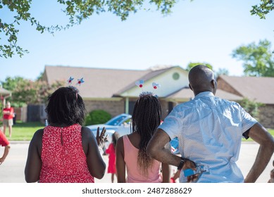 Unidentified African American families with hair hoop decoration waving hands watching Independence Day parade on residential street, July Fourth freedom celebration in Coppell, Texas, patriotism. USA - Powered by Shutterstock