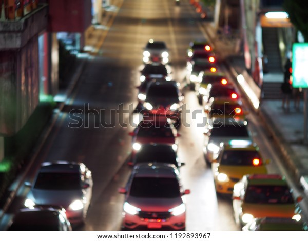 unidentified\
automobile, cars stay waiting in rows at an ample waiting for green\
traffic light in urban downtown zone blur defocused peacefully\
night life scene background on a dark\
street