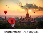 Unidentified Burmese woman holding traditional red umbrella and looks at Hot air balloon over plain of Bagan in misty morning, Mandalay, Myanmar