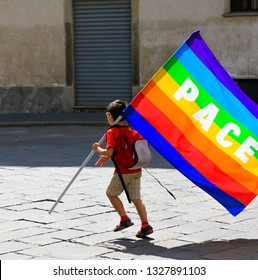 Unidentified child with rainbow flag with "peace" (Latin and Italian: Pace) written on it, in a  bad abondoned neighbourhood. Concept of world peace and no war movements