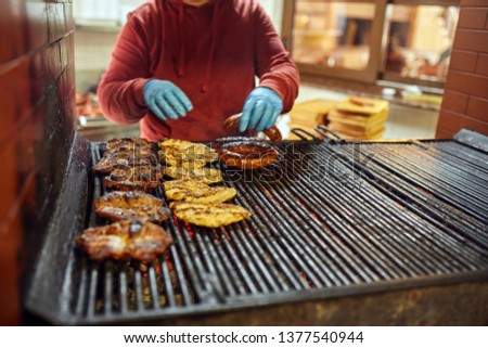 Unidentified cook grilling a variety of meats outdoor