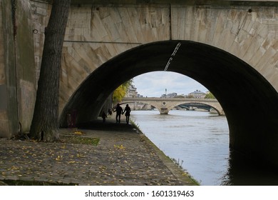 An Unidentified Couple Walking Under A Bridge Beside The Seine River In Paris, France.  Image Has Concept Of Love And Romance, And Has Copy Space.