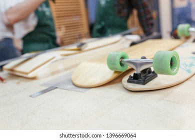 Unidentified craftsmen create wooden skateboard lying on a table in a carpentry workshop. Concept of a favorite hobby for young people - Powered by Shutterstock