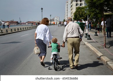 An unidentified elderly couple hold their grandson's hand as they are out for a walk at the seafront of the northern Greek city of Thessaloniki. - Powered by Shutterstock