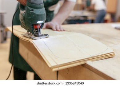 Unidentified male carpenter jigsaw out the base for a skateboard. Concept of a professional workshop for wood processing - Powered by Shutterstock