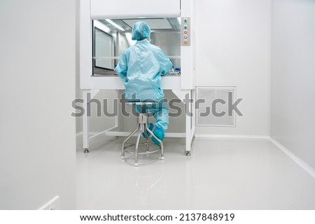 Unidentified microbiologist is testing the sample under the laminar air flow cabinet in the clean room of quality control laboratory in pharmaceutical industry.