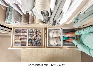 Неизвестная аккуратная домохозяйка кладет контейнер с носками и колготками на ящик шкафа во время генеральной уборки современной системой хранения. Концепция красивой и комфортной организации