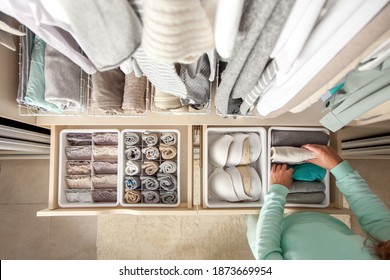 Unidentified neat housewife puts container with socks and pantyhose on wardrobe drawer during general cleaning by modern storage system. Concept of beautiful and comfortable organization - Shutterstock ID 1873669954