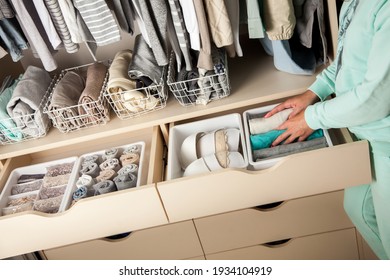 Unidentified Neat Housewife Puts Container With Socks And Pantyhose On Wardrobe Drawer During General Cleaning By Modern Storage System. Concept Of Beautiful And Comfortable Organization