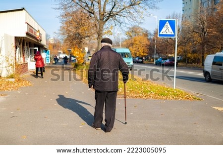 Unidentified old man with a cane walking in the city in Ukraine.