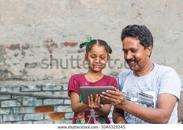 an unidentified person helps an unidentified child\
in her study on digital tablet in ludhiana, punjab, india on 15\
august 2017