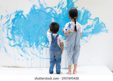 Unidentified sibling helping together to paint the wall with water color with happiness moment, concept of art education for kid, homeschooling and learn through play activity for child development.