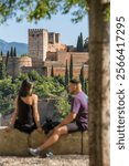 Unidentified tourists watching sunset over the city of Granada, with the historic Alhambra Palace in view. The ancient Arabic fortress Alhambra at the evening. Selective focus