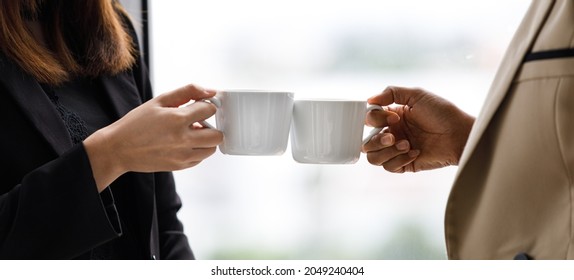 Unidentified unrecognizable businesswoman in casual business clothing standing holding white hot coffee cup clinking cheering toasting celebrating together after successful finish important work. - Powered by Shutterstock