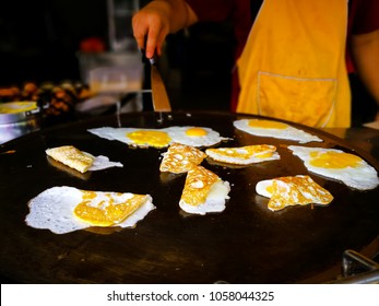 Unidentified Vendor Is Frying Eggs To Go With Nasi Lemak, Popular Street Food In Malaysia. Close Up Movement Hand The Chef Cooking Eggs On A Pan, Selective Focus.