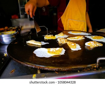 Unidentified Vendor Is Frying Eggs To Go With Nasi Lemak, Popular Street Food In Malaysia. Close Up Movement Hand The Chef Cooking Eggs On A Pan, Selective Focus.